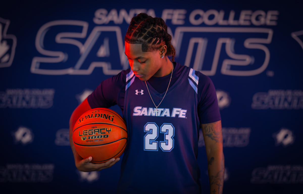  Santa Fe College Saints Women’s Basketball player Taija Lloyd holds a basketball under her arm while looking down at it.