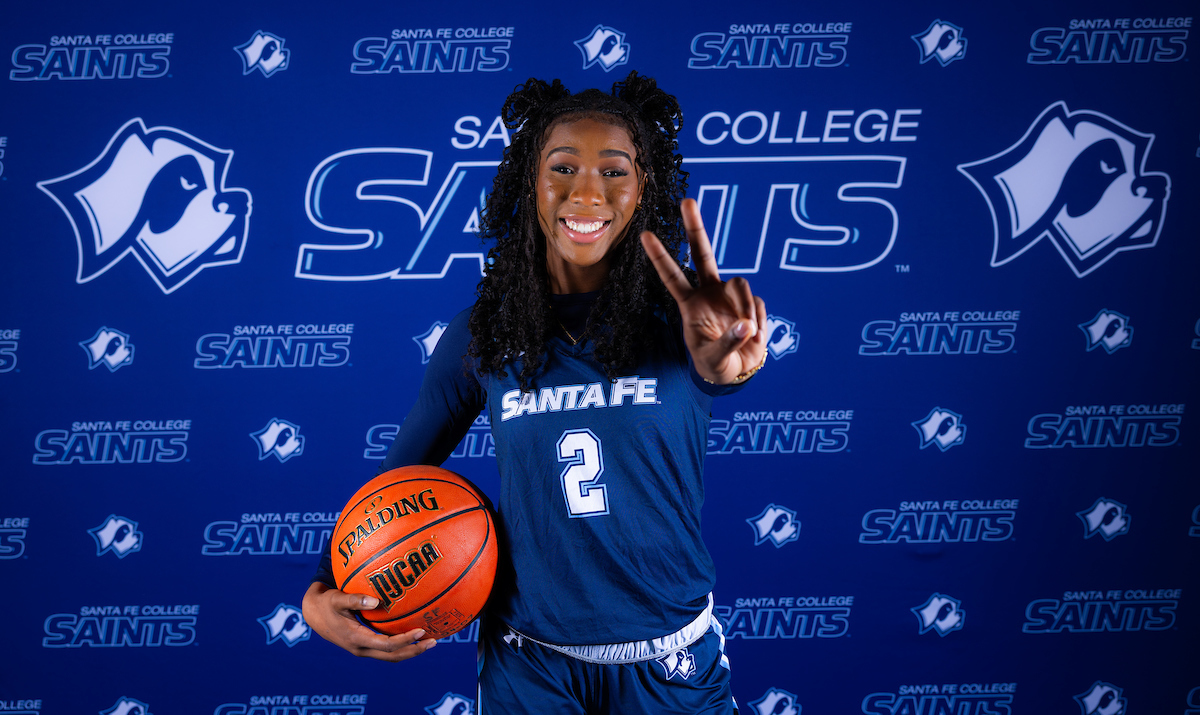 A person holding a basketball and flashing a peace sign at the camera.