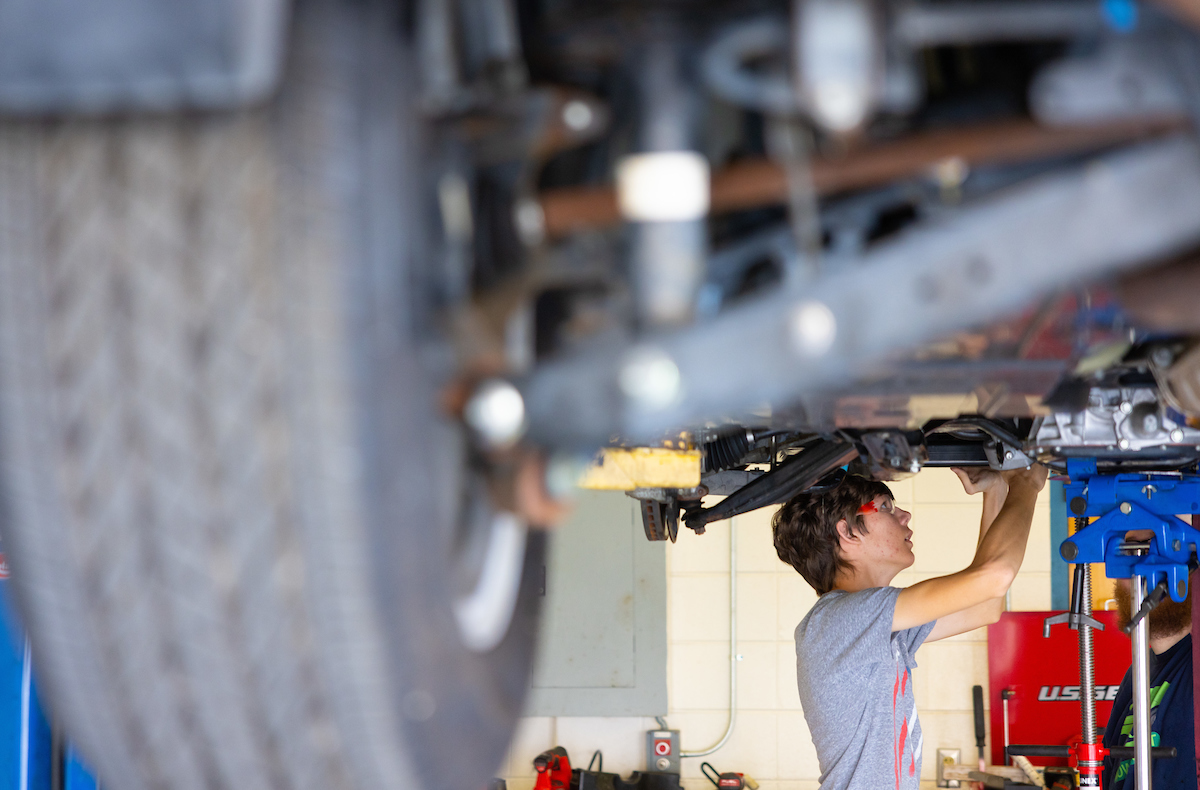 A Santa Fe College Automotive Technology student works on a car in class.