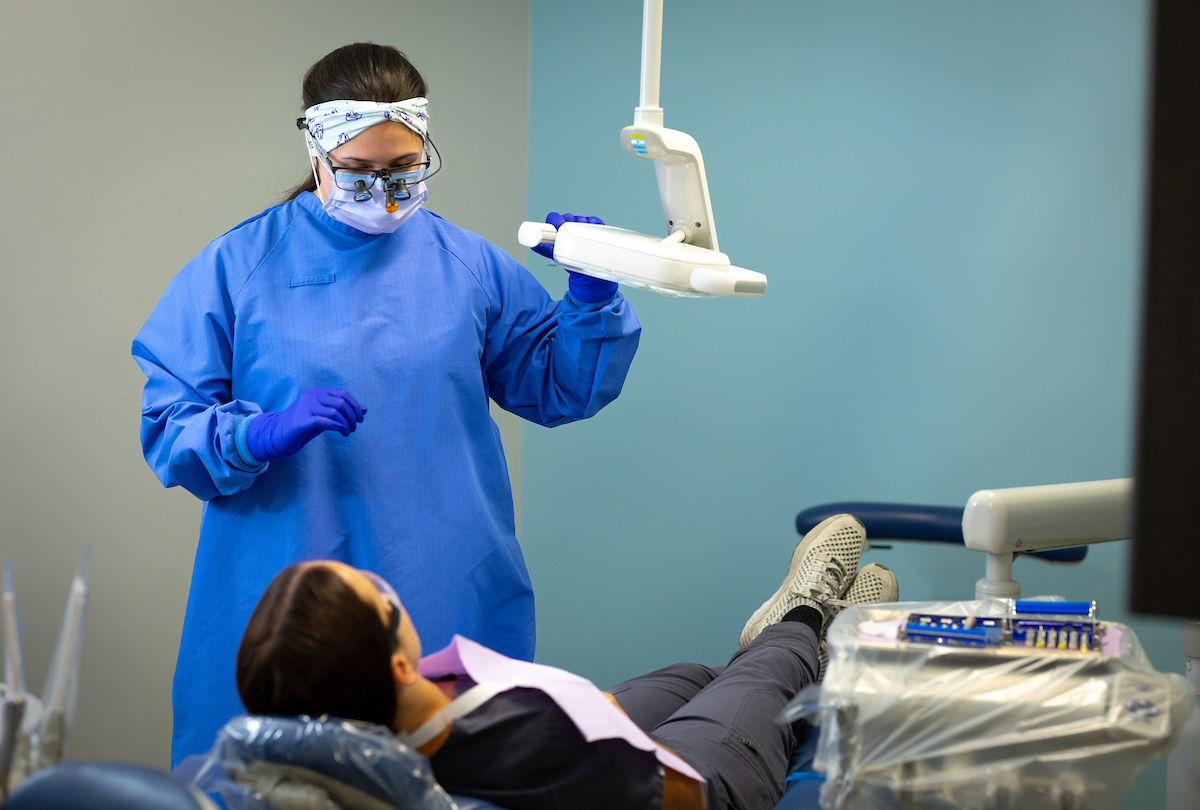 A Santa Fe College Dental Hygiene and Dental Assisting student adjusts a dental light over a patient.