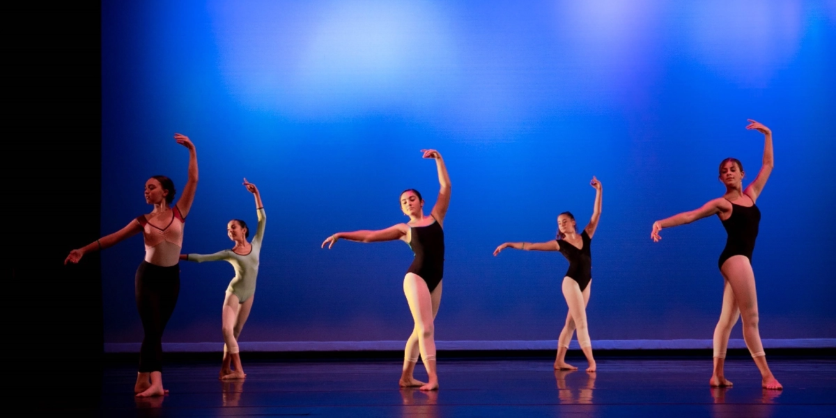 Five dancers performing on a stage.