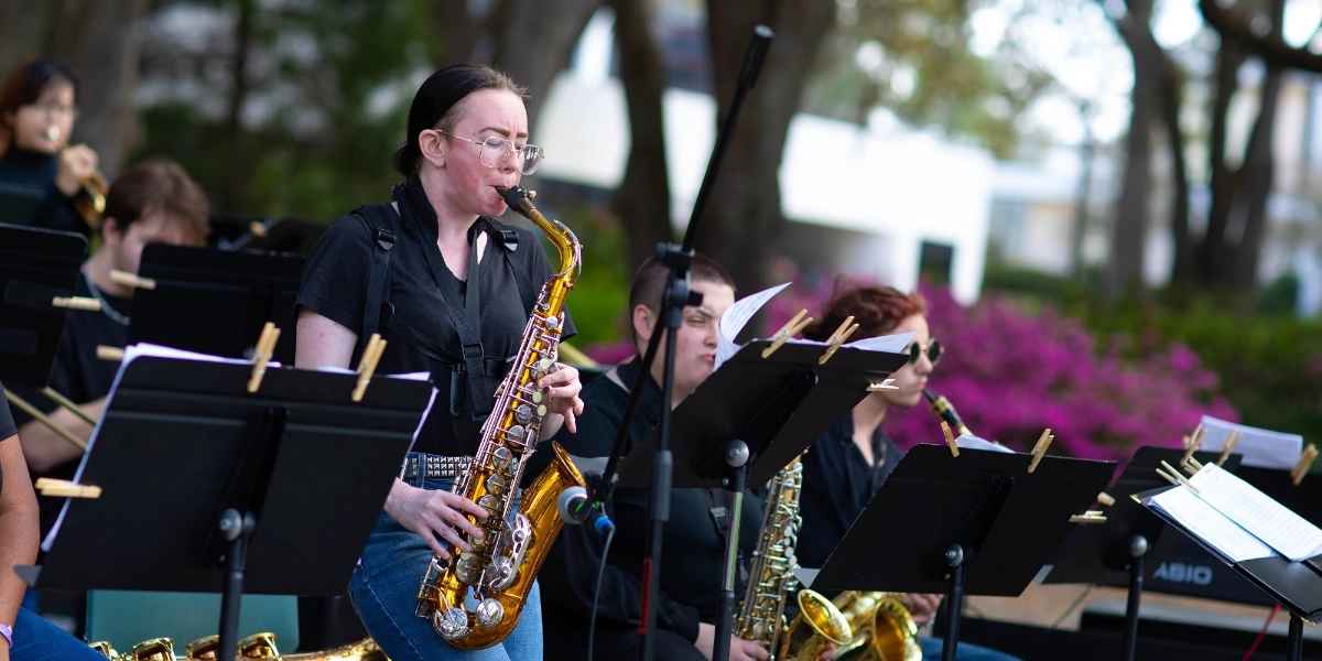 A saxophone player performs on stage with other musicians.