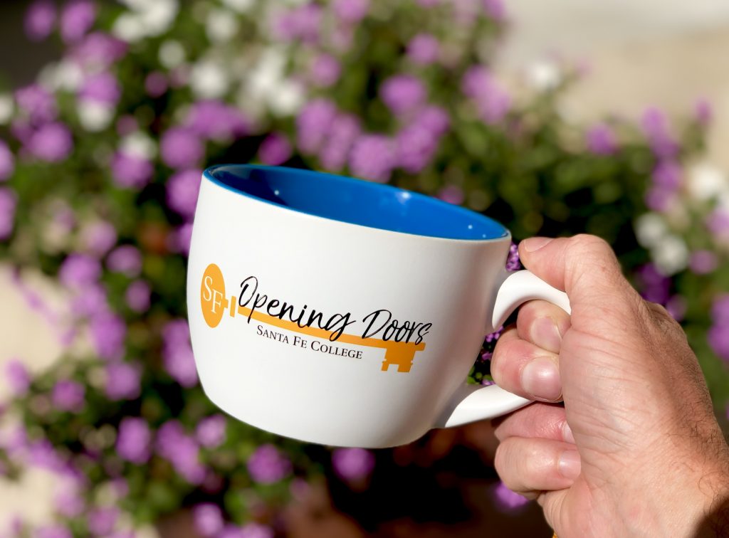 Santa Fe College Opening Doors mug photographed in front of some azaleas
