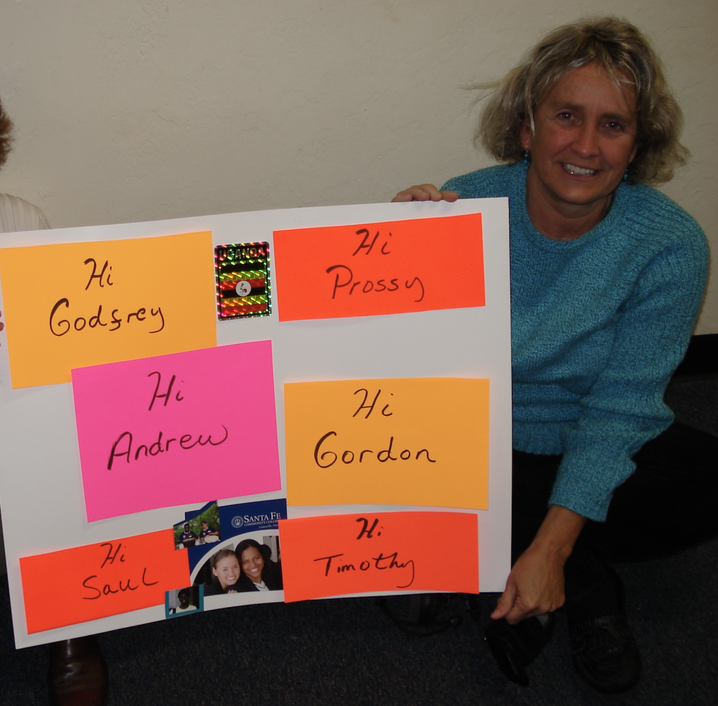 Carol Thomas in Africa holding a poster board sign with names of friends