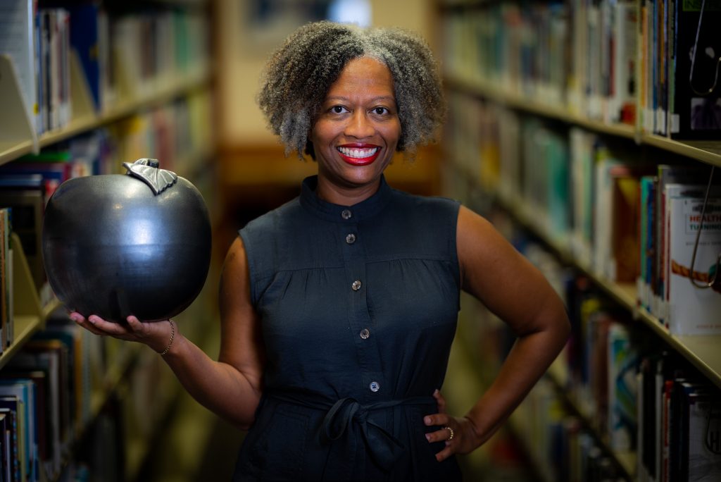 Santa Fe College Associate Professor Katherin Garland, PhD holding a giant apple statue