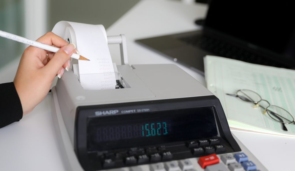 A hand holding a pencil over a calculator