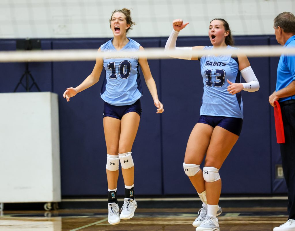 two volleyball players yelling next to a referee