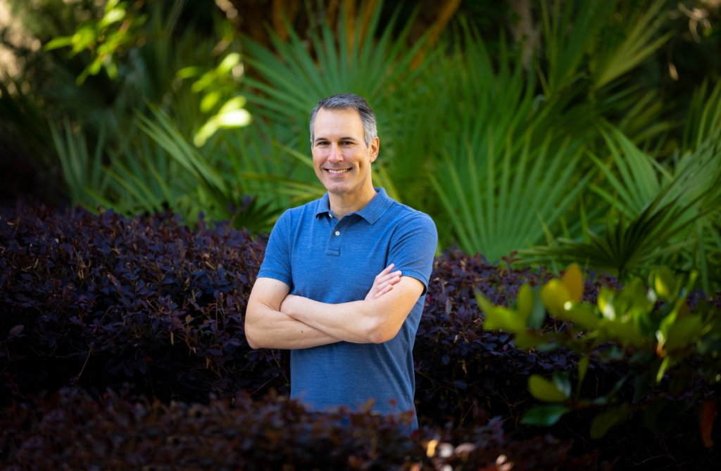 Andy Sheppard smiling and standing with their arms folded