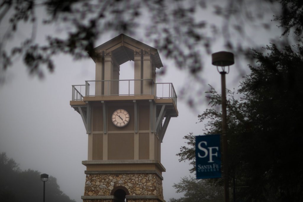 The Santa Fe College clocktower with a pole banner reading "SF Santa Fe College" on the right