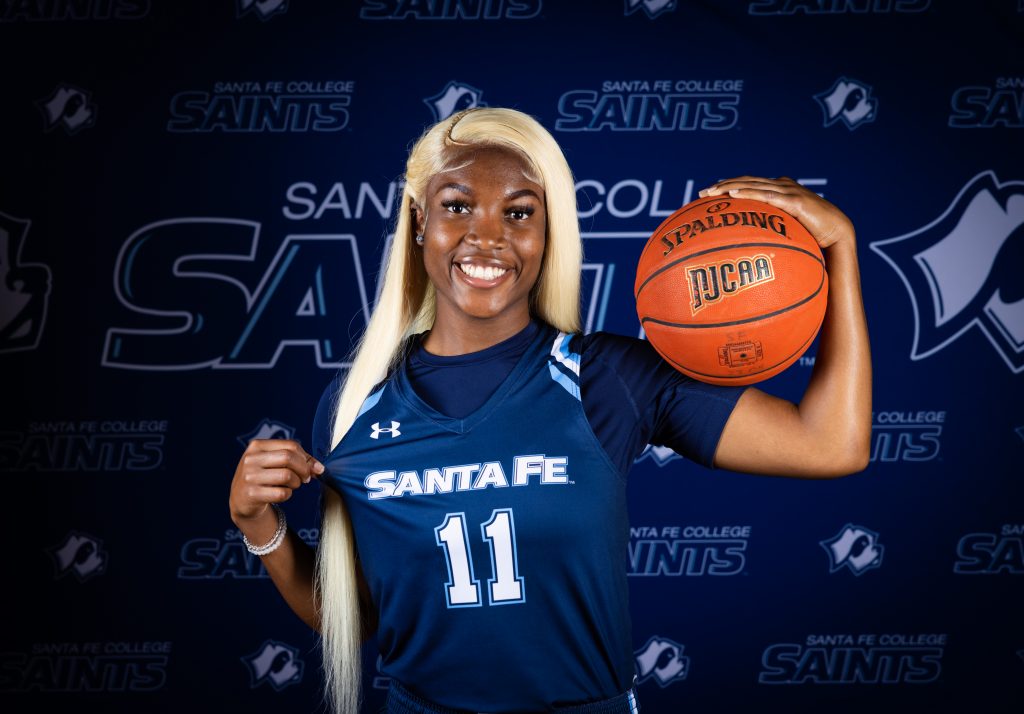 Santa Fe College Saints Women’s Basketball player Leyah Houston  holds a basketball on her shoulder.