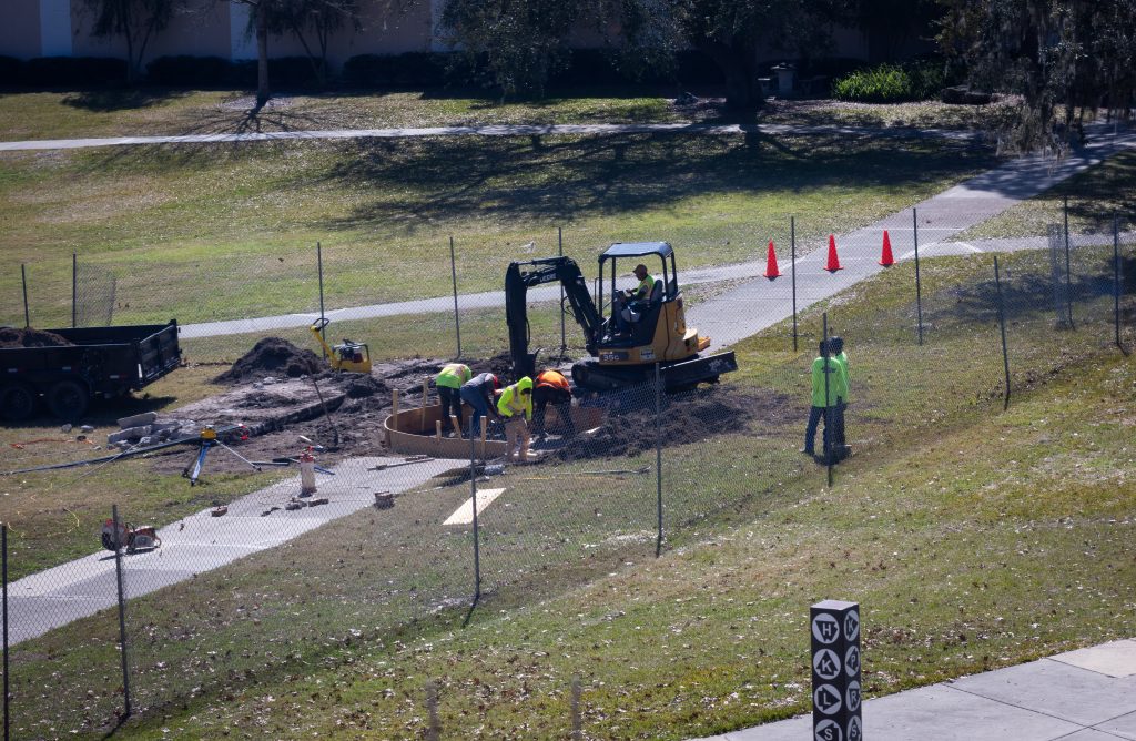 Crews work to install a piece of artwork on the Santa Fe College Oak Grove.