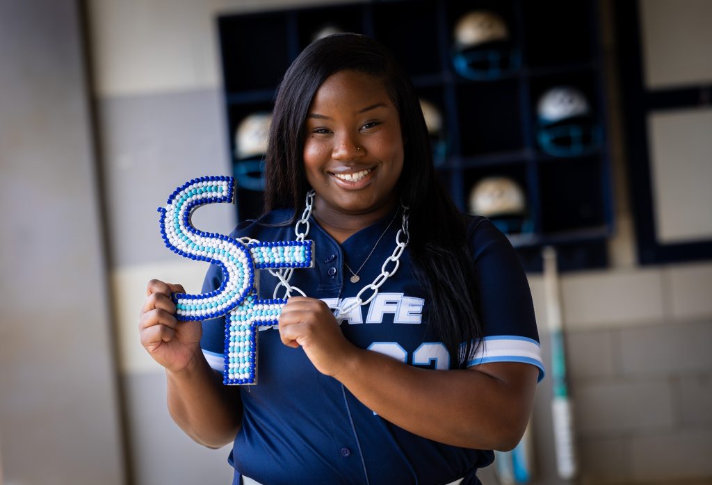 Santa Fe College Saints Softball player Ariana Wright smiles while holding up the letters 