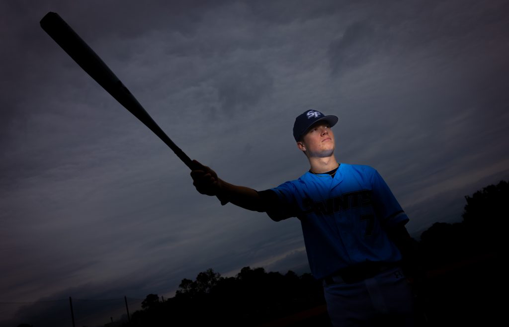 Santa Fe College Saints Baseball player Javier Soto holds a baseball bat up.