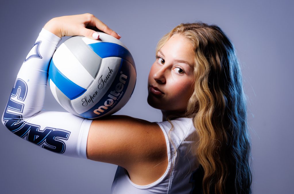 An individual holding a volleyball on their bicep.